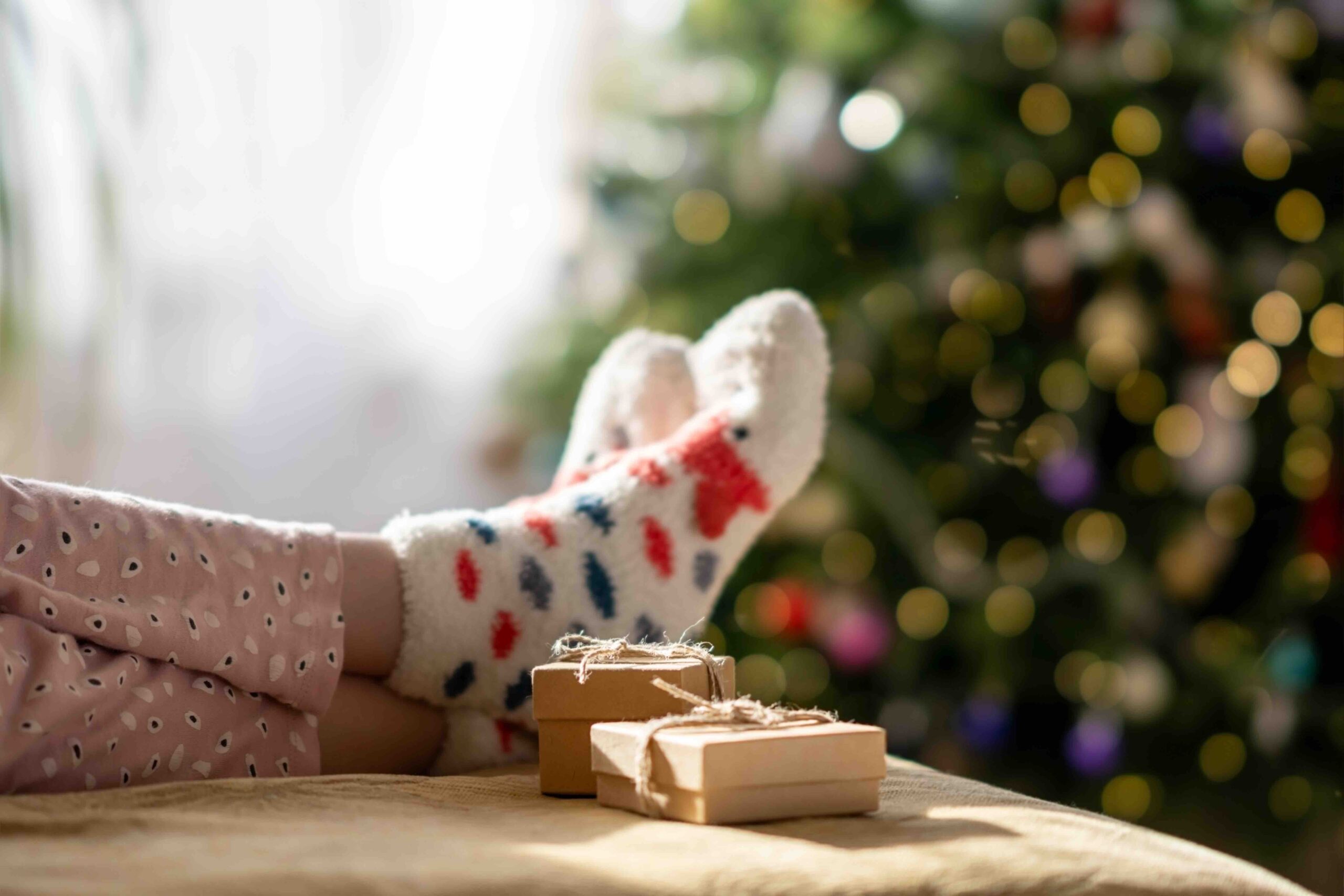 Preparing for Christmas. Children's feet in Christmas socks lie on the sofa opposite the Christmas tree.